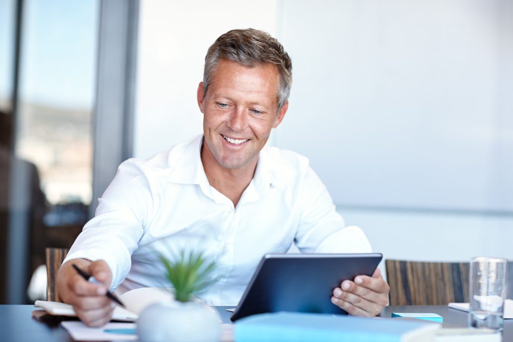 staying top things shot handsome businessman using digital tablet office - Clés de succès pour Directeurs Financiers : compétences, défis et préparation au recrutement